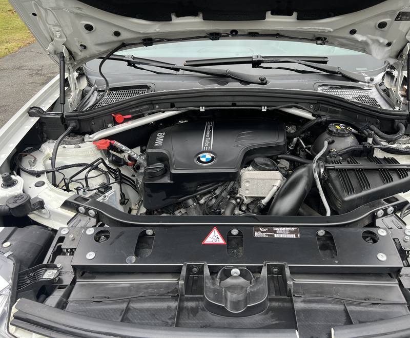 Mobile engine bay cleaning in Charlotte: BMW X3 engine bay with a clean engine cover and plastics