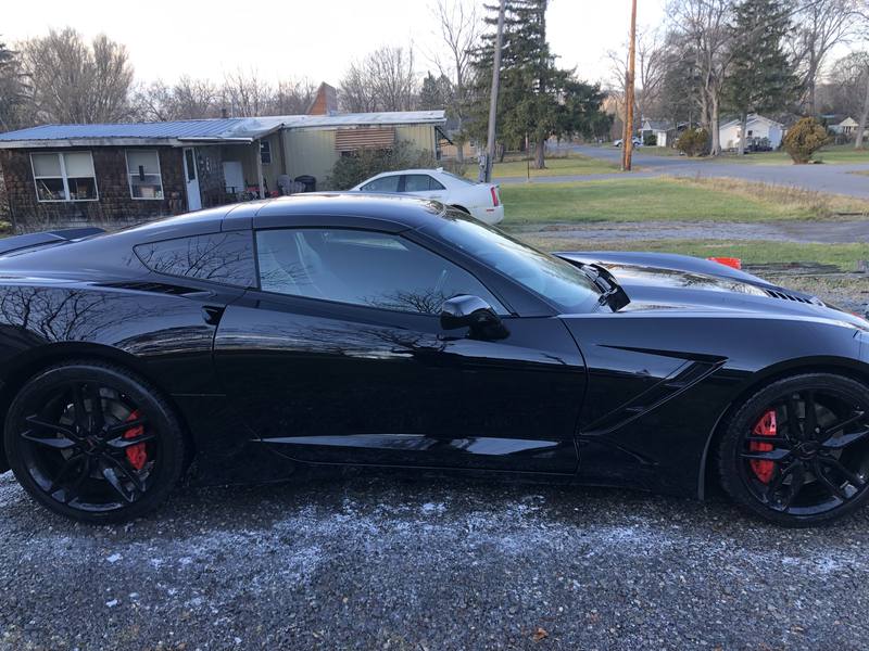 Mobile ceramic coating in Charlotte: Side profile of a black C7 Corvette Stingray with mirror-like paint reflections after a detail