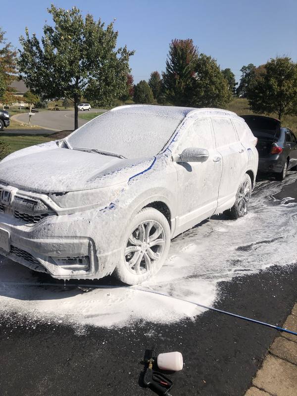 Mobile exterior detailing in Charlotte: White Honda CR-V covered in thick foam during a mobile hand wash in a driveway