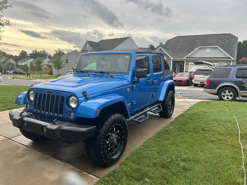 Mobile car detailing in Monroe, NC: Blue Jeep Wrangler Unlimited in a driveway after a mobile wash, with the detailing van parked nearby