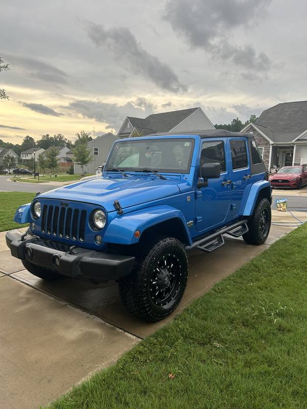 Mobile wash and wax in Charlotte: Blue Jeep Wrangler Unlimited with black wheels and shined tires after a wash