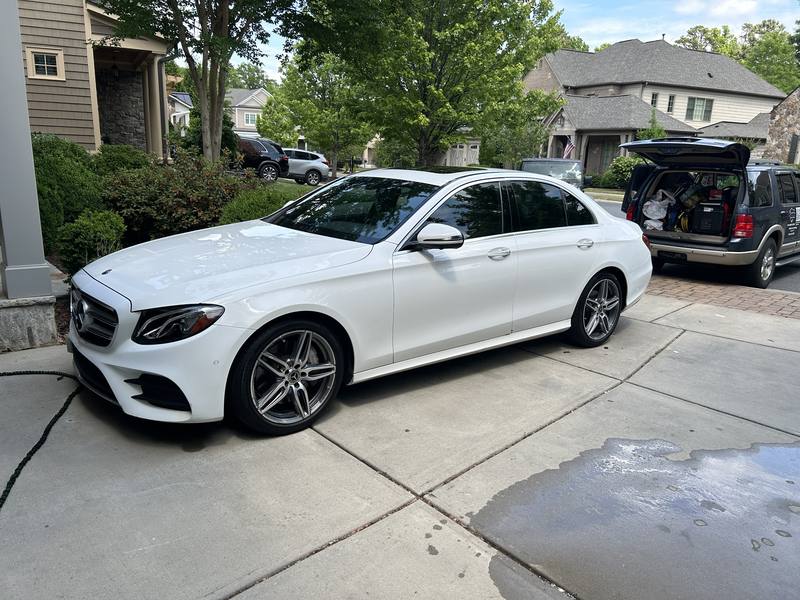 Mobile exterior detailing in Charlotte: White Mercedes-Benz E-Class in a driveway after a mobile detail, with the detailing SUV parked nearby