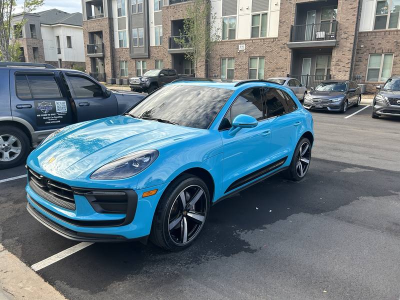 Mobile car detailing in Charlotte, NC: Bright blue Porsche Macan with glossy paint next to the Motion Mobile Detailing van